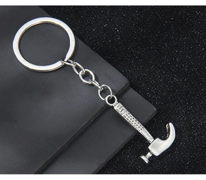 Détail d'un porte-clés marteau arrache-clous miniature en métal sur fond sombre