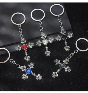 Detailed close-up of gothic cross keychains with relief roses and heart-shaped crystals