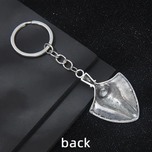 Vintage silver metal shovel keychain with antique texture shown from back view angle