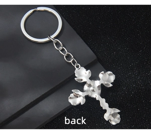 Detail view of the silver cross keychain back side with intricate textured pattern