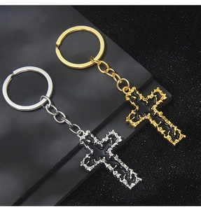 Macro detail of gothic gold and silver cross keychains with black drip oil finish