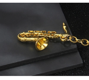 Detailed macro view of a vintage golden saxophone keychain on a sleek black background