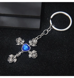 Close-up of vintage rose cross keychain featuring a blue heart gemstone in silver metal