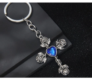 Macro detail of gothic rose cross keychain with a blue heart crystal on a black stone