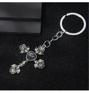 Macro detail of gothic silver cross keychain with heart stone and 3D rose carvings