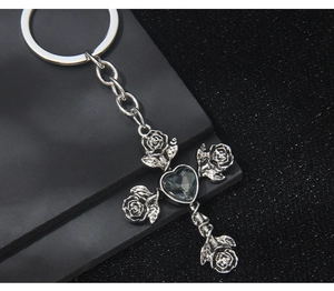Macro shot of gothic rose cross keychain with heart center on dark textured background