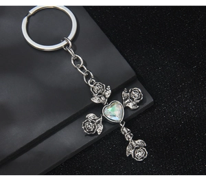 Detailed view of Gothic silver cross keychain with metallic roses and heart opal stone