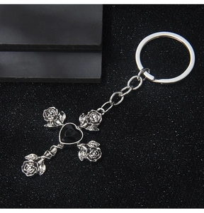 Gothic silver keychain with rose cross pendant and black heart gem on a textured background