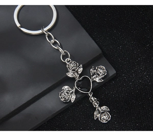 Macro shot of gothic cross keychain with silver roses and a black heart gem detail