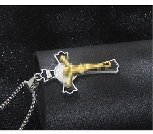 Macro detail of gothic cross necklace with golden Jesus figure and metallic bead chain