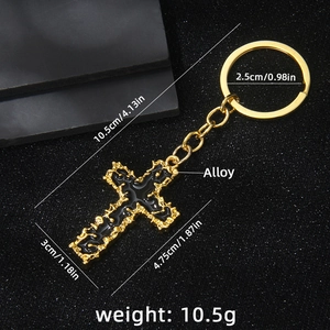 Vintage golden alloy cross keychain with black enamel detail on textured background