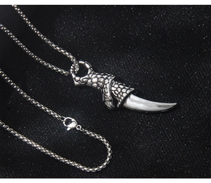 Detailed macro view of the dragon claw holding a wolf tooth pendant in vintage silver