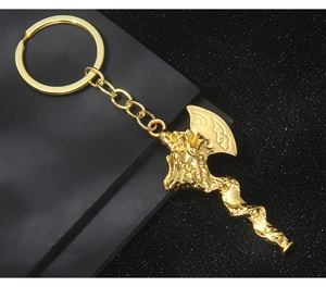 Close-up of golden dragon Viking axe keychain with embossed texture on dark background