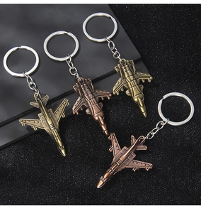 Detailed close-up of four vintage metal fighter jet keychains in varied antique finishes