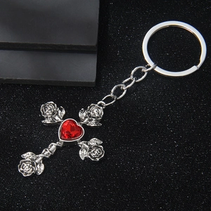Gothic silver cross keychain with red heart gemstone and rose flower details on black background