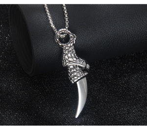 Macro view of a silver dragon claw pendant holding a polished wolf tooth on black leather