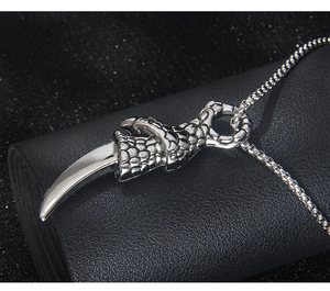 Detailed close-up of a silver dragon claw pendant with intricate scales on black leather