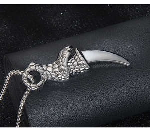 Detailed close-up of a dragon claw pendant clutching a white tusk on a black leather stand