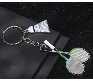 Detailed close-up of a shuttlecock and crossed rackets keychain on a textured background