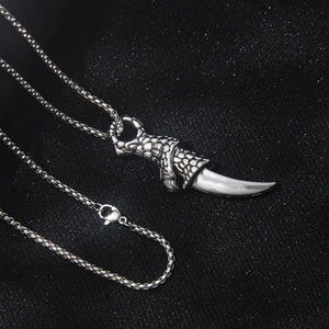 Gothic dragon claw and tooth pendant necklace with silver box chain on black fabric