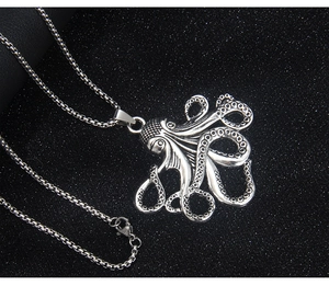 Gros plan détaillé d'un pendentif pieuvre en argent avec des textures sur fond noir