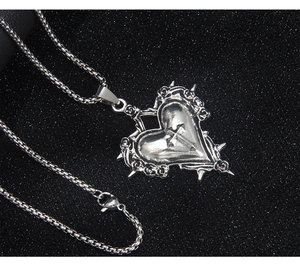 Détail du pendentif cœur gothique avec relief d'épines et croix sur chaîne argentée