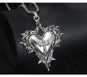 Vue détaillée d'un pendentif cœur gothique avec croix et roses sur cuir noir