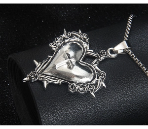 Gros plan du pendentif cœur gothique avec croix et roses sur une chaîne maille box
