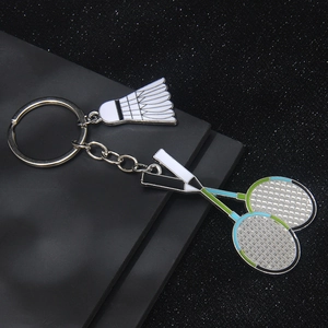 Badminton shuttlecock and crossed rackets metal keychain on a sleek black display stand