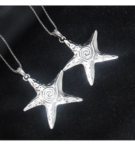 Vue détaillée de pendentifs étoile de mer argentés avec texture martelée sur fond noir