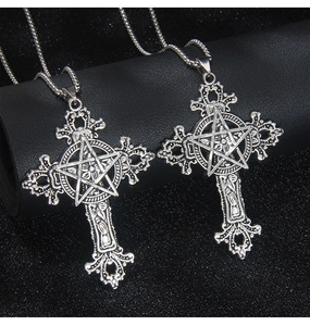 Close-up of vintage stainless steel gothic cross necklace with pentagram on black display