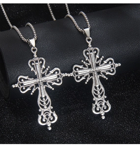 Detailed macro view of two vintage silver cross pendants with intricate baroque filigree