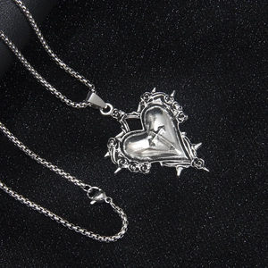 Collier gothique cœur et croix avec épines et roses sur fond noir scintillant