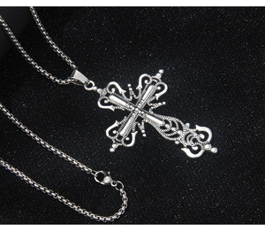 Macro view of silver Baroque cross necklace with intricate filigree on black background