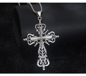 Macro shot of retro silver cross pendant with intricate Baroque floral carvings on black leather
