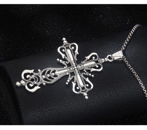 Close-up of a silver gothic hollow cross pendant with intricate vintage carvings on a bead chain