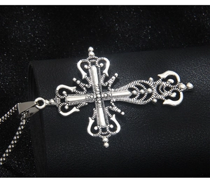 Macro shot of vintage silver cross pendant with intricate baroque scrollwork details
