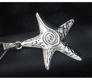 Vue macro du collier pendentif étoile de mer argentée avec texture cratère et spirale