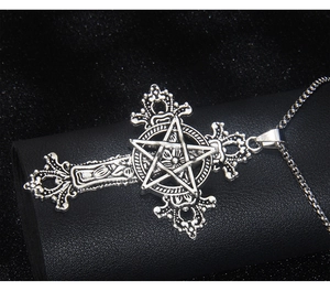 Close-up of gothic stainless steel cross necklace with star and floral engraving