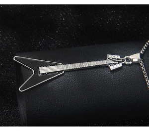 Macro shot of silver-tone electric guitar pendant with black enamel inlay and cross chain