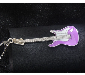 Makro-Detail von lila-weißem Gitarrenanhänger mit silberner Kette auf schwarzem Leder