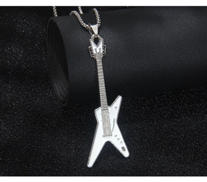 Détail macro du pendentif guitare électrique argentée avec émail blanc sur chaîne box