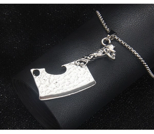 Detail of vintage silver skull meat cleaver pendant with engraved patterns on black leather