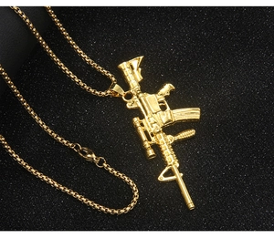Macro shot of detailed golden AR-15 rifle pendant on box chain over black texture