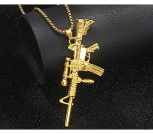 Macro shot of gold plated AR-15 rifle pendant on box chain with industrial details