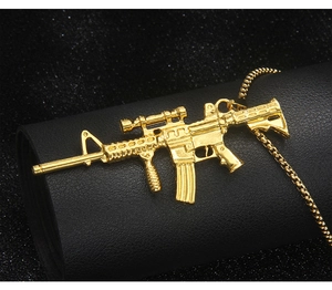 Detailed close-up of a golden metal assault rifle pendant on a black leather display