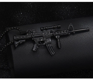 Macro detail of a black metal assault rifle pendant with a high-gloss finish and bead chain