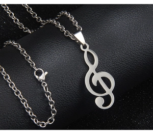 Gros plan d'un pendentif clé de sol en argent sur fond en cuir noir texturé élégant