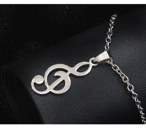 Gros plan d'un pendentif clé de sol en argent poli sur une surface en cuir noir