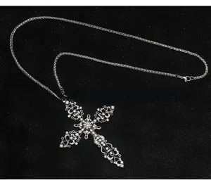 Gros plan d'un collier croix punk argenté avec strass brillants et chaîne tressée épaisse